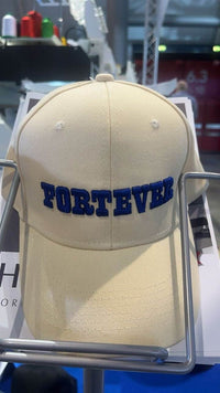Beige caps med blå "FORTEVER"-brodering, som viser presisjon fra en industri broderimaskin med avanserte funksjoner. ✅