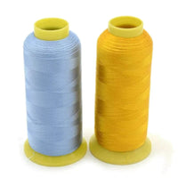 Two spools of Flores polyester embroidery thread in light blue and yellow from a 100-color thread pack, ideal for machine embroidery with vibrant, durable, and high-strength threads.