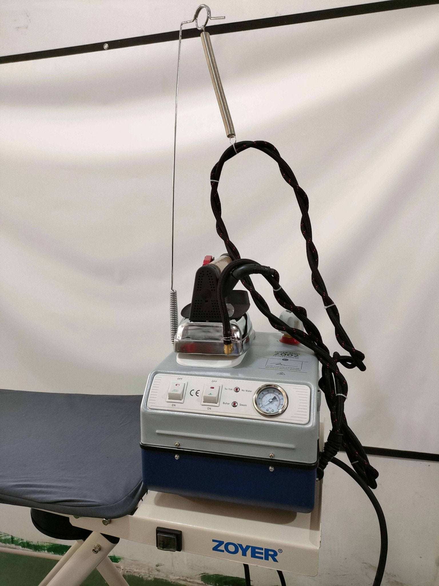 Zoyer steam iron with vacuum board on ironing station for professional use